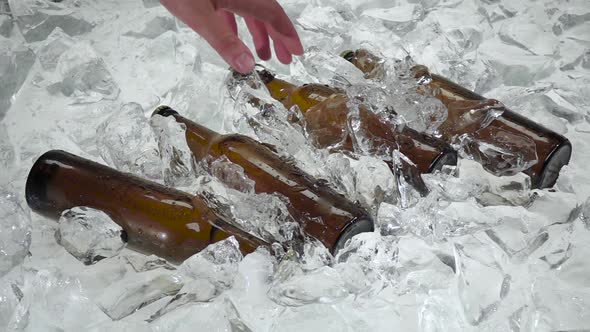 Man's Hand Pulls One Bottle From the Ice. White Background. Slow Motion alt