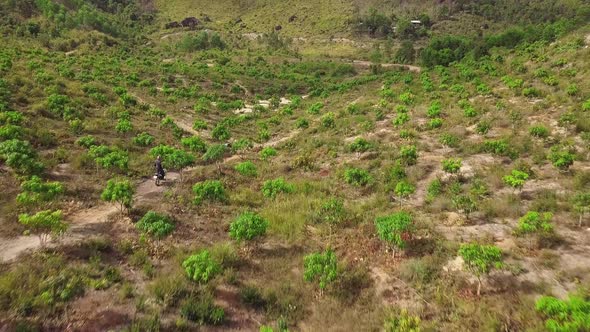 A Motocross Rider Riding Motorbike on the Dirt Road Pathway in the Mountain. alt