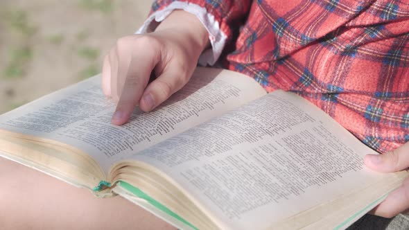A Schoolgirl Girl Holds a Textbook in Her Hands and Reads Something Carefully