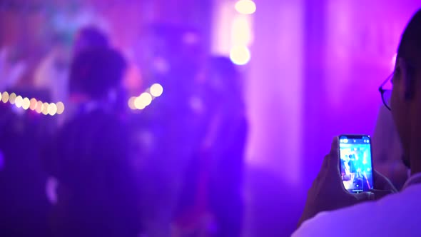 Black Man Films with Smartphone Dancing People in Nightclub