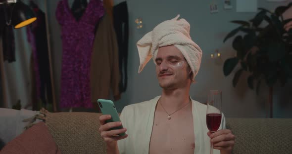 Close Up of Relaxed Trans Man in Home Wear Using Smartphone and Drinking Wine. Young Transgender alt