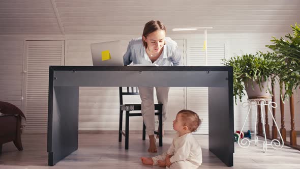 A Young Mother is Working at Home Using Computer While She's Taking Care of Her Baby alt