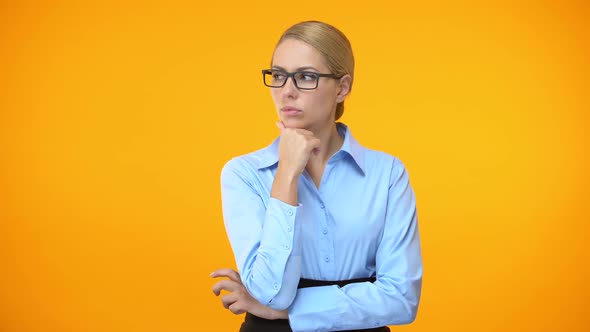 Thoughtful Woman Looking Right and Left on Orange Background, Difficult Choice alt