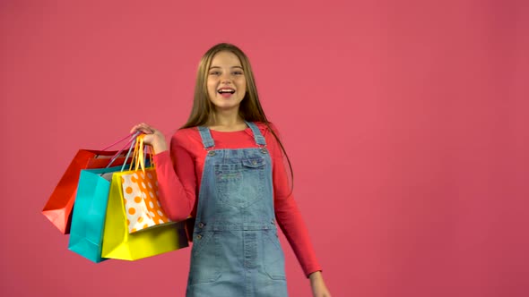Teen with Bags in Their Hands and Rejoices at Their Purchases. Pink Background alt