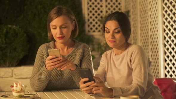 Two Female Friends Looking Photos and Gossiping, Using Mobile App for Social Net alt