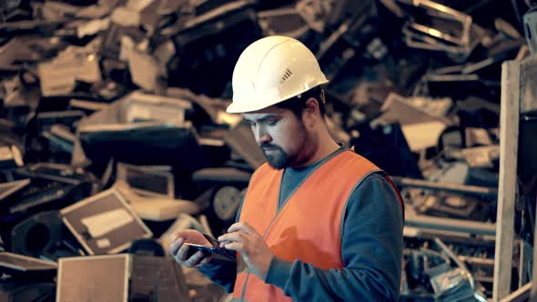 Dumpsite Worker with a Smartphone and Garbage in the Background alt