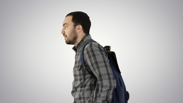 Portrait of man putting backpack on on gradient background. alt