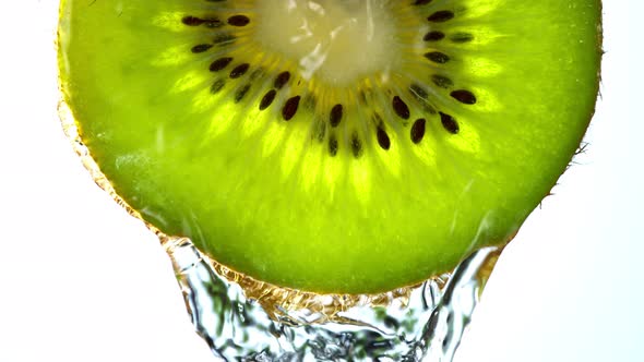 Super Slow Motion Macro Shot of Flowing Water From Kiwi Slice on White Background at 1000Fps alt