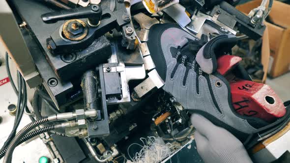 Factory Worker Using a Shoe Making Machine at a Footwear Facility. Close Up alt