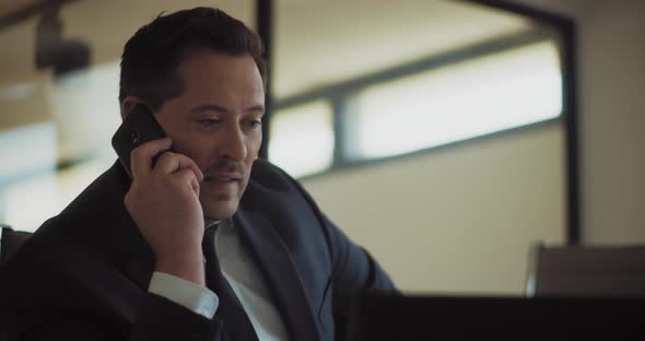 Close up of a businessman talking on the phone while working from his office. Slow motion alt