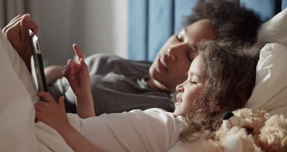 Mother and Daughter Playing Game on Tablet alt