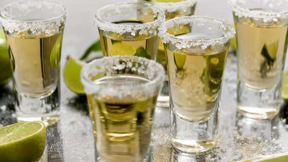 Golden Tequila Shots Served with Lime and Sea Salt on Table