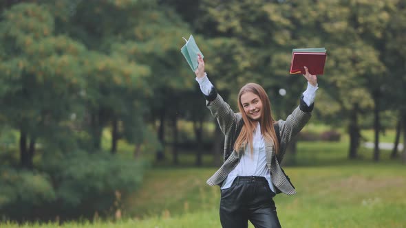 A Cheerful Student with Books in the Park in the Summer alt