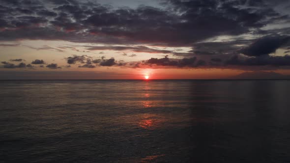 Amazing Aerial of Orange Sunset Above Ocean Water Reflecting Sun Rays Shot with Drone Flying