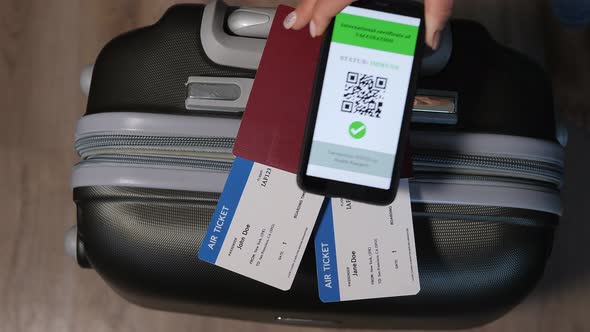 Mobile Phone with a Digital Vaccination Certificate Near Passport and Suitcase alt