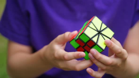Boy in blue t-shirt holding Rubik's cube. Teenage boy playing with square colorful toy. alt