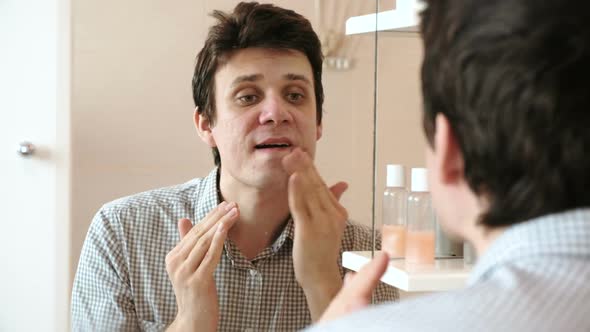 Man Puts Cream on His Face After Shaving While Looking in the Mirror