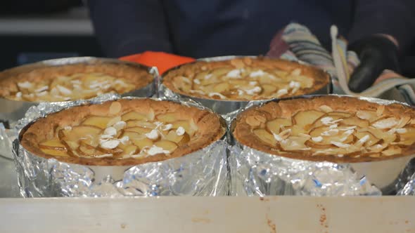 Pastry Baker Put on the Table a Baking Sheet with Many Baked Pear and Almond Pies in Metal Round