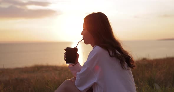 Young Woman Drinking Takeaway Cocoa at the Nature alt