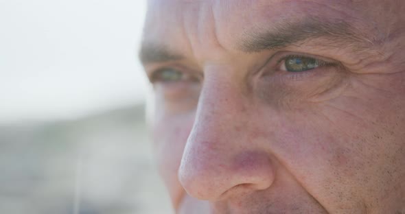 Close up of Caucasian man enjoying free time by sea on sunny day looking away alt