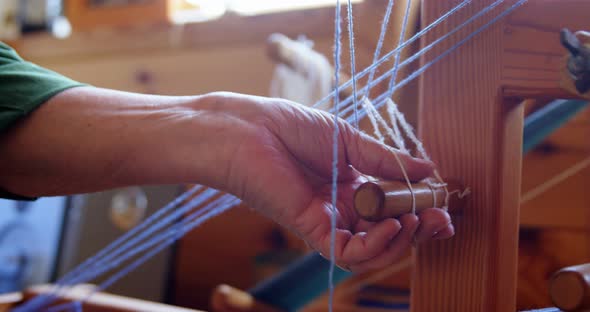 Senior woman placing woollen thread on weaving machine 4k alt