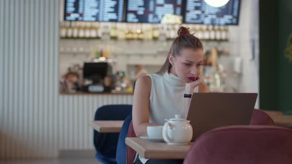 Attractive Longhaired Casually Dressed Girl Working Intently Wit Laptop in Cafe