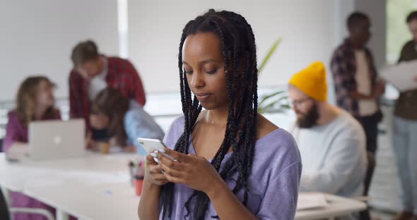 Smiling Afroamerican Businesswoman Using Phone in Modern Busy Office alt