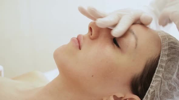 Beautician doing massage of female faces. Massage face girl close-up