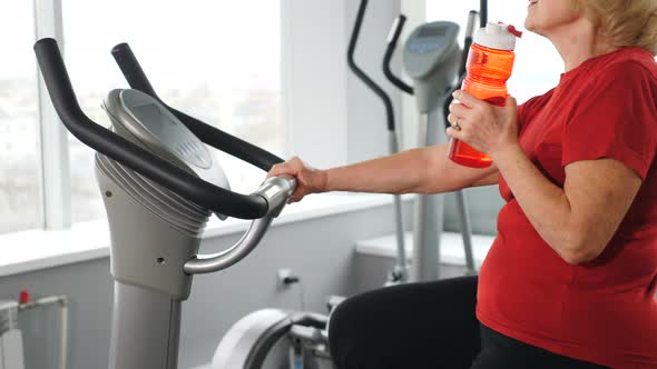 Unrecognizable Senior Caucasian Woman Drinking Water From Bottle During Workout on Training alt