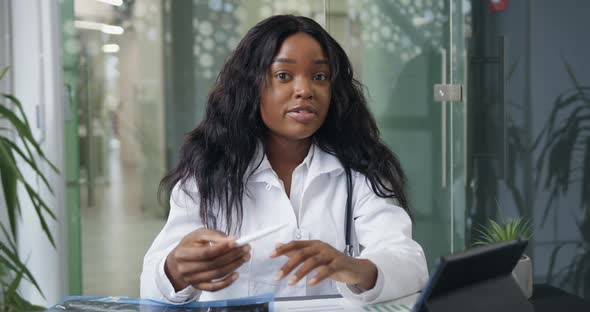 Emale Doctor in white Gown with Stethoscope which Holding Video Conference and Consulting partners alt
