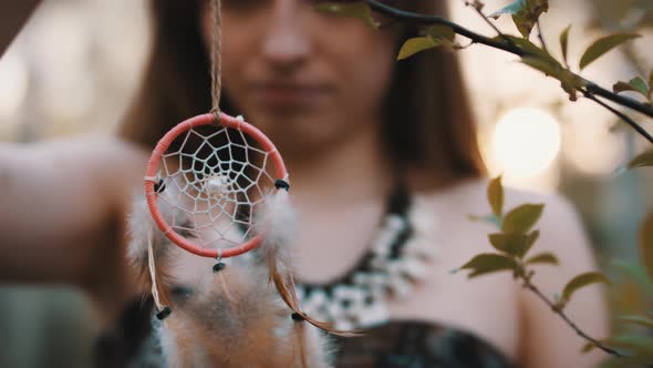 Young Woman Spinning the Dreamcatcher. Close Up. Spirituality and Connection with the Nature Concept alt