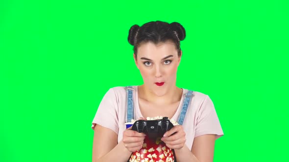 Girl Playing a Video Game and Chews Popcorn on a Green Screen, Slow Motion alt