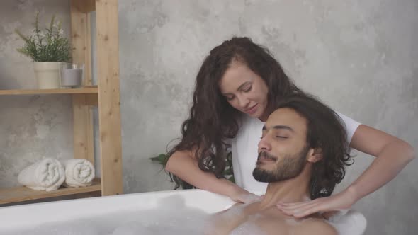 Woman Massaging Shoulders of Man while He Taking Bath alt