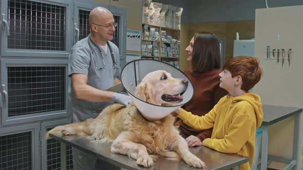 Portrait Of Veterinarian With Dog And Its Owners alt