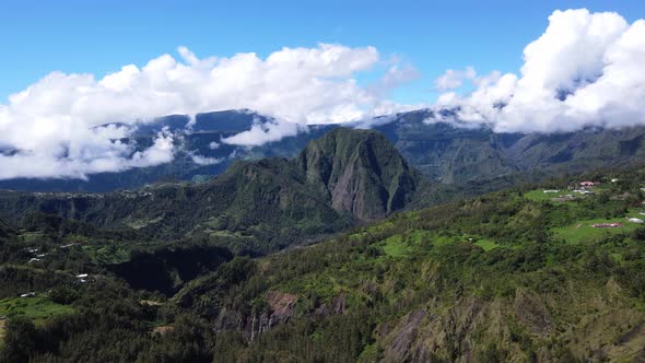 Drone footage of the Cirque de Salazie at the Reunion Island with mountains and clouds. alt