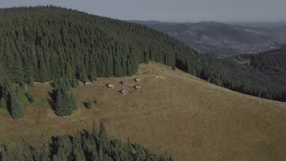 Aerial view of wooden houses on an carpatian meadow among mountains alt