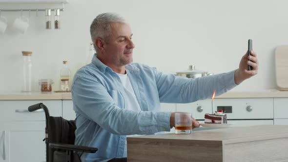 Man In Wheelchair Making Selfie With Birthday Cake At Home alt