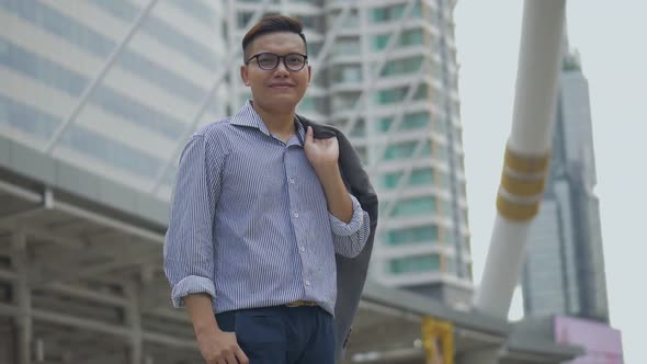 Portrait handsome Asian businessman smiling and looking at camera standing on the urban city.