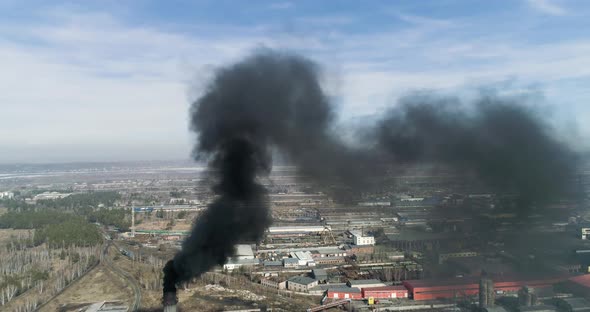 Aerial footage of coal-fired plant smokestack. Black smoke cloud is coming from chimney. alt