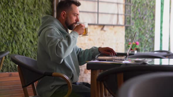 Man Drinking Tea and Using Laptop in Cafe