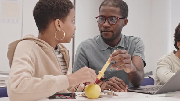 Girl and Teacher Experimenting with Lemon and Wires alt