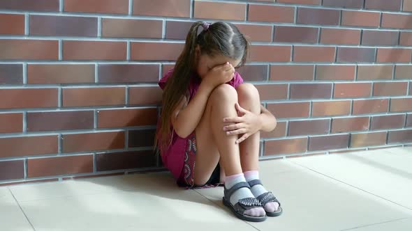 Child Abuse. Little Girl Crying, Sitting on the Floor