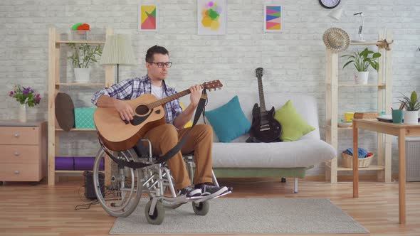 Young Disabled Man in a Wheelchair Musician Plays Guitar alt