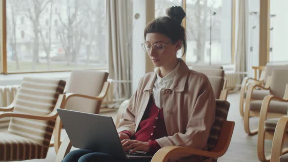 Young Woman Working on Laptop in Library Auditorium alt