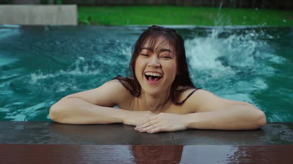slow-motion of woman hold on to the edge of the swimming pool and splashing water with her feet