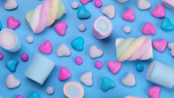 Rotating Chewing Marshmallows Candies Dragees and Sweets on a Blue Background Closeup Top View the