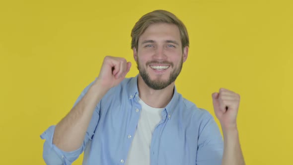 Young Man Dancing in Joy on Yellow Background alt