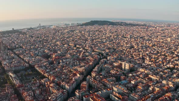 Dolly back drone shot over winding streets of north Barcelona Gracia at sunrise alt