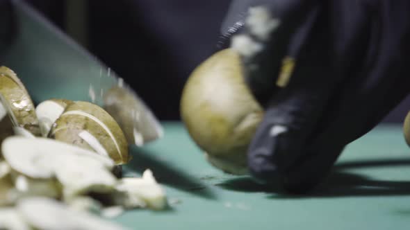 Cook's Hands in Black Gloves Slicing Mushrooms Close Up Selective Focus alt