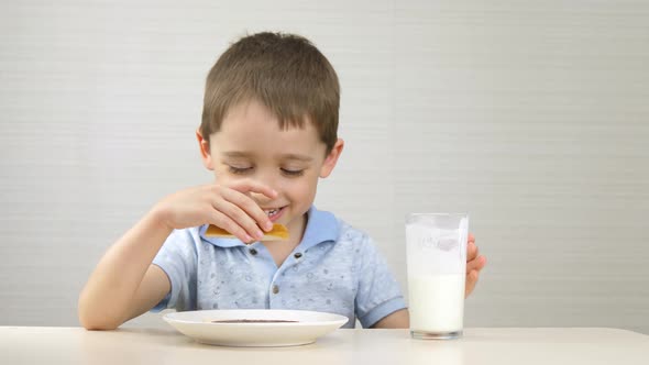 The Child Drinks Milk and Eats a Sandwich. The Boy Eats a Sandwich with Chocolate Paste and Drinks a alt